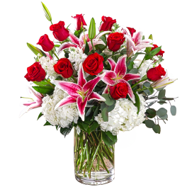 Bouquet of red roses and pink lilies in a clear glass vase