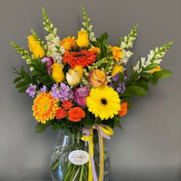 Colorful mixed bouquet in a clear glass vase with ribbon