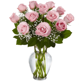Arrangement of light pink roses with white filler flowers in a clear glass vase