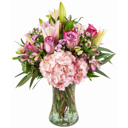 Pink lilies, roses, and hydrangeas in a clear glass vase