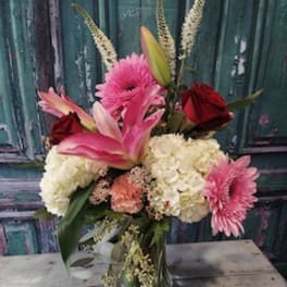 Pink lilies, roses, and hydrangeas in a glass vase