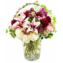 Mixed bouquet of roses, lilies, and hydrangeas in a glass vase