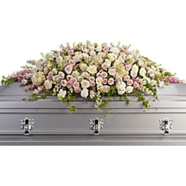 White and pink floral casket spray on a silver casket