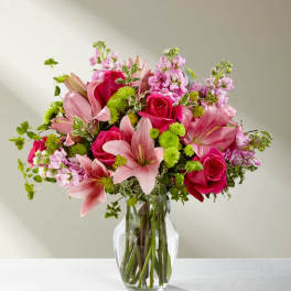 Pink lilies and roses arranged in a clear glass vase