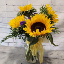 Sunflower bouquet in a glass vase with yellow ribbon