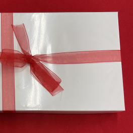 Rectangular white gift box with a sheer red ribbon and bow on a red background