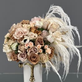 Bouquet of blush and beige roses in a white vase with white feathers
