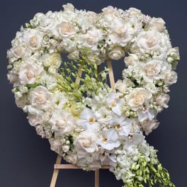 Heart-shaped white floral wreath on a wooden easel