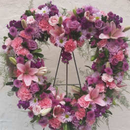 Heart-shaped floral wreath with pink and purple flowers on a stand