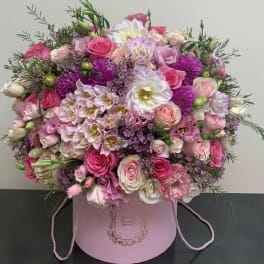 Pink and white mixed flower arrangement in a round pink box