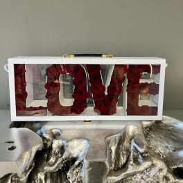 White box with red roses arranged to spell LOVE