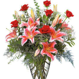 Red roses and pink lilies in a clear glass vase