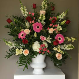 Large mixed flower arrangement in a white urn vase