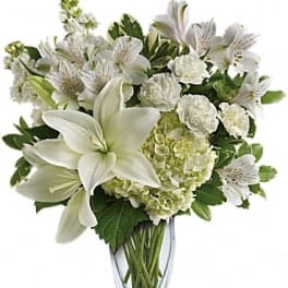 White lilies and hydrangeas arranged in a clear glass vase