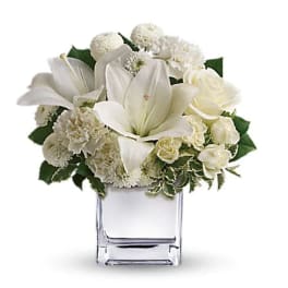 White lilies and roses arranged in a clear glass vase