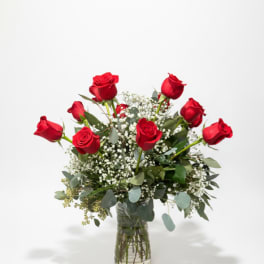 Red roses arranged in a clear glass vase with white filler flowers