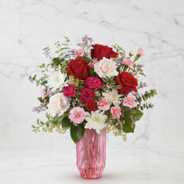 Bouquet of red and pink flowers in a pink glass vase