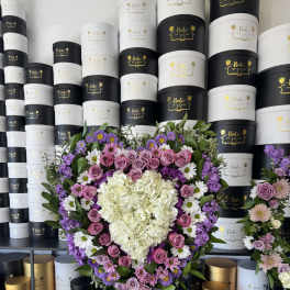 Heart-shaped floral arrangement with pink roses, white hydrangea, and purple flowers