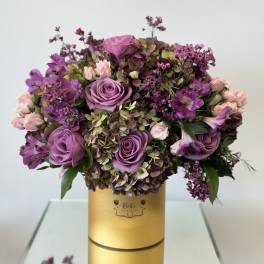 Purple and pink rose bouquet in a gold hatbox