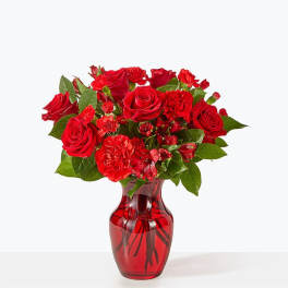 Red roses and carnations in a red glass vase