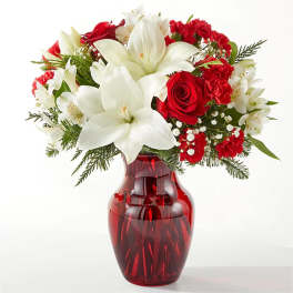 Red and white floral arrangement in a red glass vase
