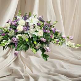 Low floral arrangement of white lilies, roses, and lavender blooms