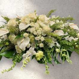 White floral casket spray with roses and orchids