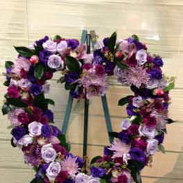 Heart-shaped floral wreath on an easel with purple and pink flowers