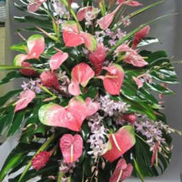 Pink anthuriums and small lilac flowers in a large standing arrangement