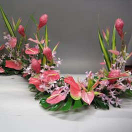 Pink floral garland with tall green leaves on a table