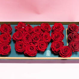 Red roses arranged in a rectangular gift box on a pink background