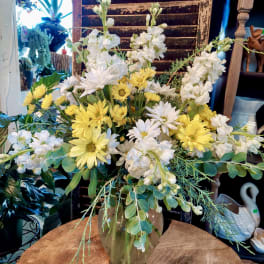 White and yellow flowers arranged in a glass vase