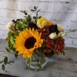 Sunflower and mixed autumn flowers in a clear glass vase