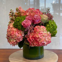 Pink and peach hydrangeas with roses in a green glass vase