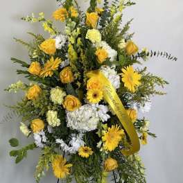 Tall yellow and white sympathy spray on an easel with ribbon