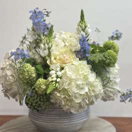 White and blue floral arrangement in a gray bowl vase