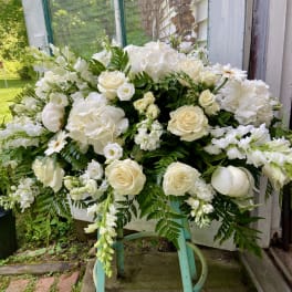 Large white floral arrangement with roses and hydrangeas on a stand