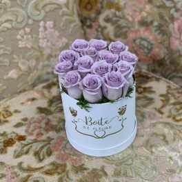 Lavender roses arranged in a white round box