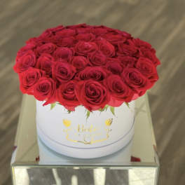 Round box of red roses on a mirrored table