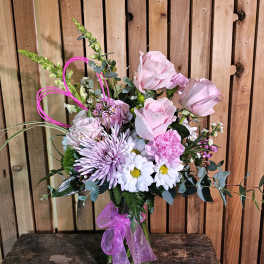 Pink and lavender bouquet in a glass vase with a purple ribbon