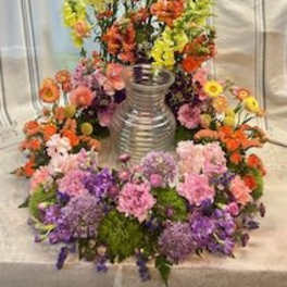 Large colorful floral arrangement around a silver vase