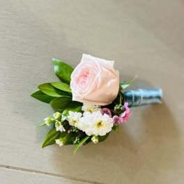 Pink rose boutonniere with small white and pink flowers