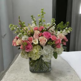 Pink and white roses with hydrangeas in a clear glass vase