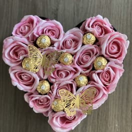 Heart-shaped arrangement of pink roses with gold-wrapped chocolates and butterfly picks