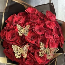 Bouquet of red roses with gold butterfly accents in black wrapping