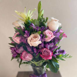 Bouquet of pink and purple flowers in a glass vase with a ribbon