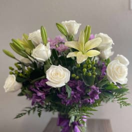 White roses and lilies with purple flowers in a glass vase