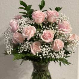 Pink roses arranged in a clear glass vase with baby's breath