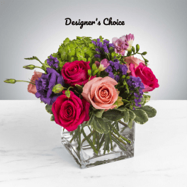 Mixed bouquet of roses, lisianthus, and purple filler in a clear square vase