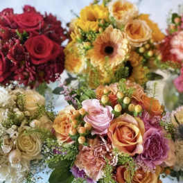 Assorted bouquets of roses, gerbera daisies, and carnations in warm colors